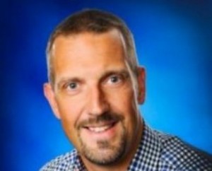 Marko Heinonen puhuu mikrofoniin, taustalla hevosurheilukeskuksen piirustuksia