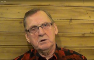 Sulo Kallio soittaa kitaraa hymyillen, taustalla mikrofoni ja kaiutin
