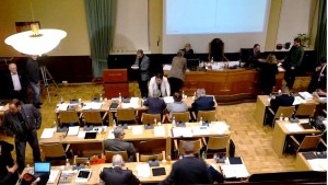 Valtuustosali, jossa on tyhjiä tuoleja ja pöytiä