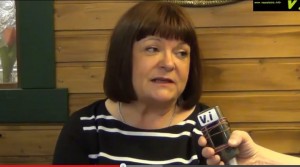 Maria Tolppanen puhuu, taustalla vaaleansininen seinä