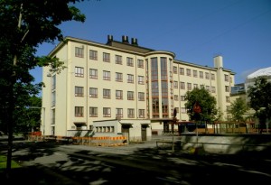 Oppilaita opiskelemassa luokkahuoneessa, opettaja taustalla