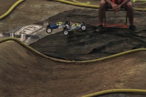 Motocross-kuljettaja hyppää radalla, yleisö seuraa taustalla