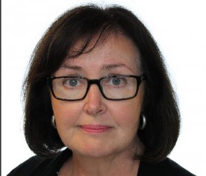 Tuija Pitkäkoski hymyilee, taustalla hämärä ravintolaympäristö