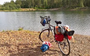 Jari Laurila pyöräilemässä maaseudulla, kirkko taustalla