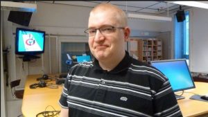 Lauri Karppi puhuu, taustalla Perussuomalaisten logo