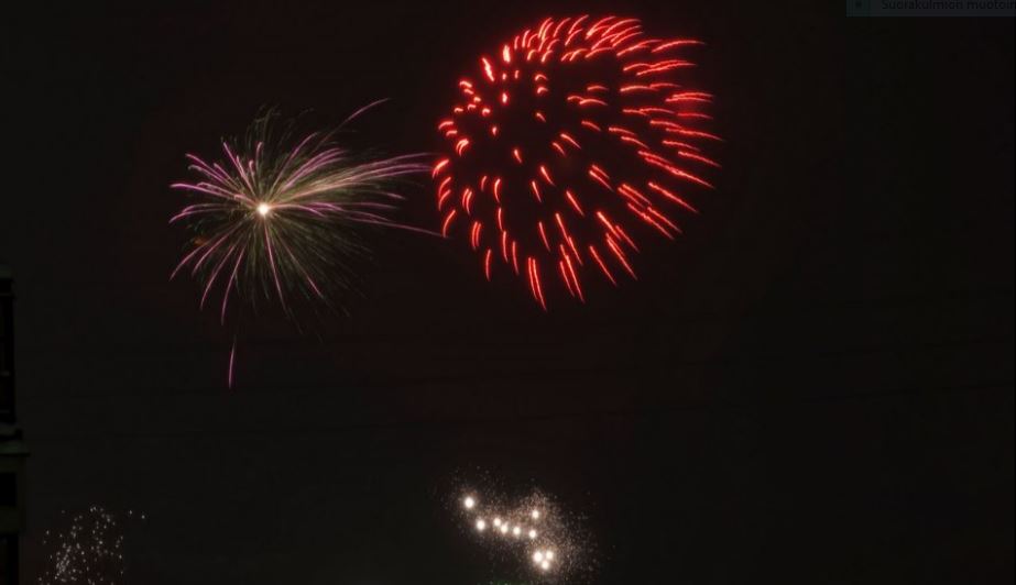 Värikkäitä ilotulitteita valaisee pimeää iltataivasta