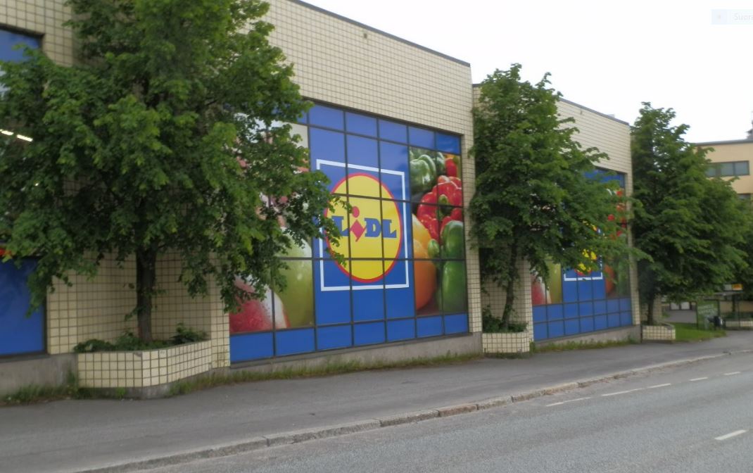 Lidl-myymälän edustalla hymyilevä nainen ja kaksi lasta