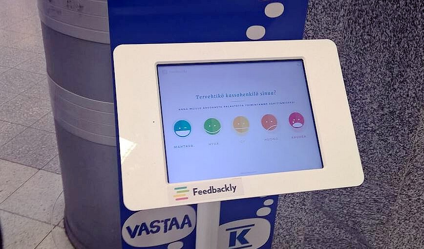 Asiakas hymyilee ja katsoo puhelintaan, taustalla somekuvakkeita