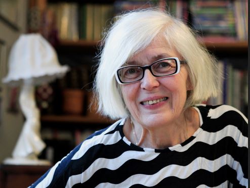 Idiko Lehtinen puhuu sukukansoista, taustalla seinävaate