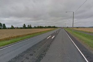 Lakeusmaisema, jossa peltoja ja metsää, taustalla rakennuksia