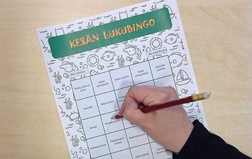 Lapsi lukee kirjaa, taustalla lukubingoruudukko