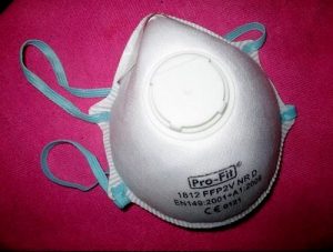 Henkilö pitää hengityssuojainta kasvoillaan katupölyltä suojautuakseen