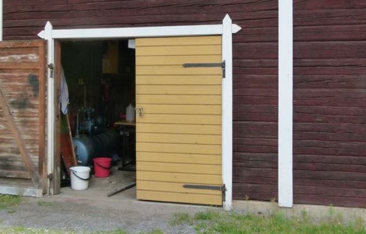 Vanha puinen liiteri, jossa on puinen ovi ja pieni ikkuna