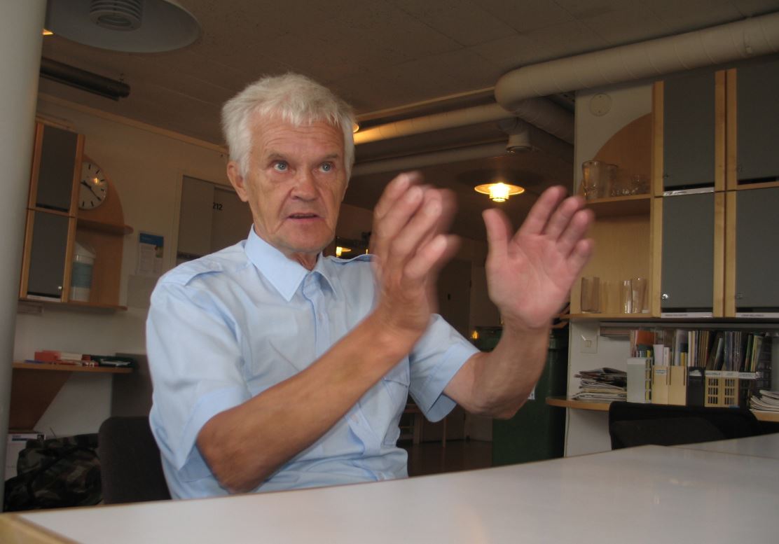 Jussi Kangas hymyilee kameralle, taustalla kirjahylly