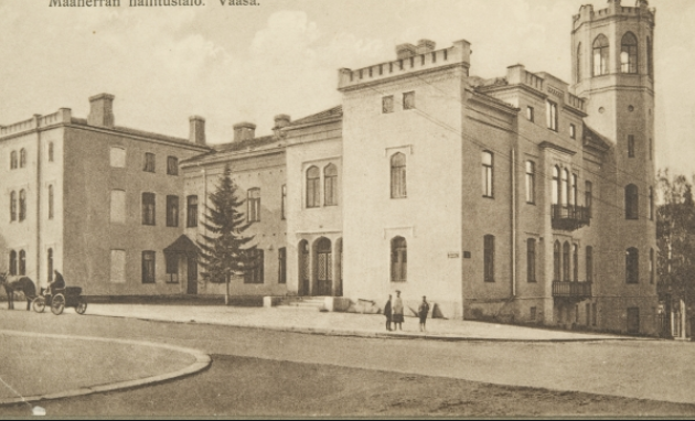 Maaherrantalo, kaksikerroksinen valkoinen rakennus, puita ja pensaita edustalla