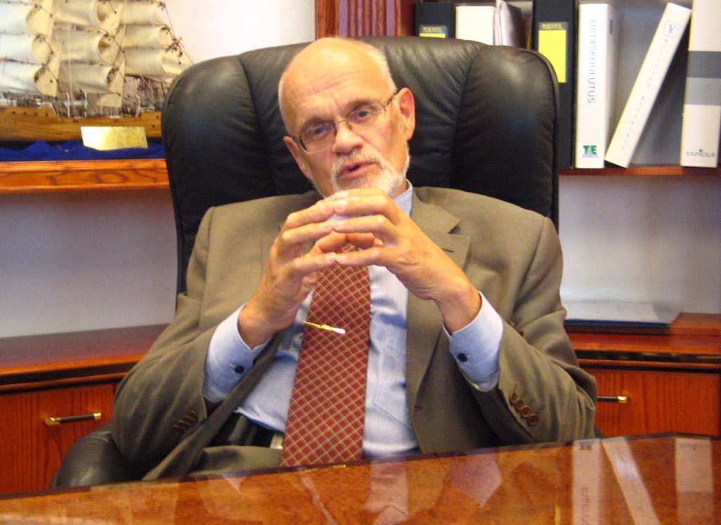 Pentti Tarpio hymyilee kameralle, taustalla toimistoympäristö